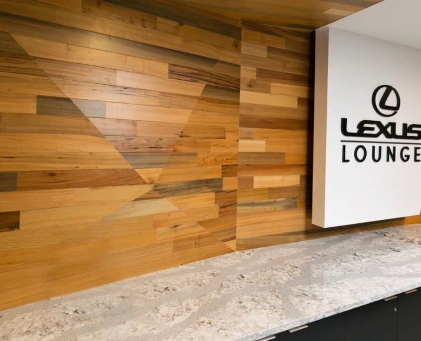 Lexus Lounge interior with wood-paneled wall, countertop, and logo sign.