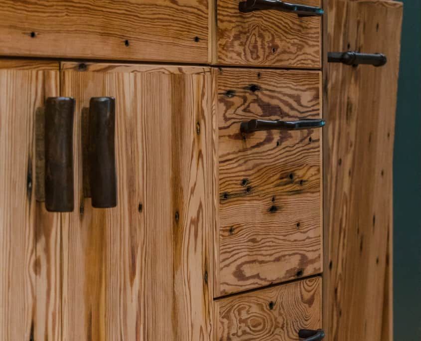 Wooden cabinet with dark metal handles and exposed wood grain.