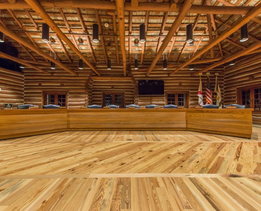 Wooden paneled meeting room with a large table, flags, and a television.