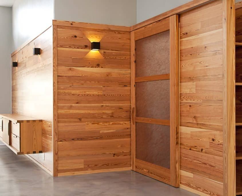 Wooden built-in storage unit with sliding door. Contains light fixtures and shelves.