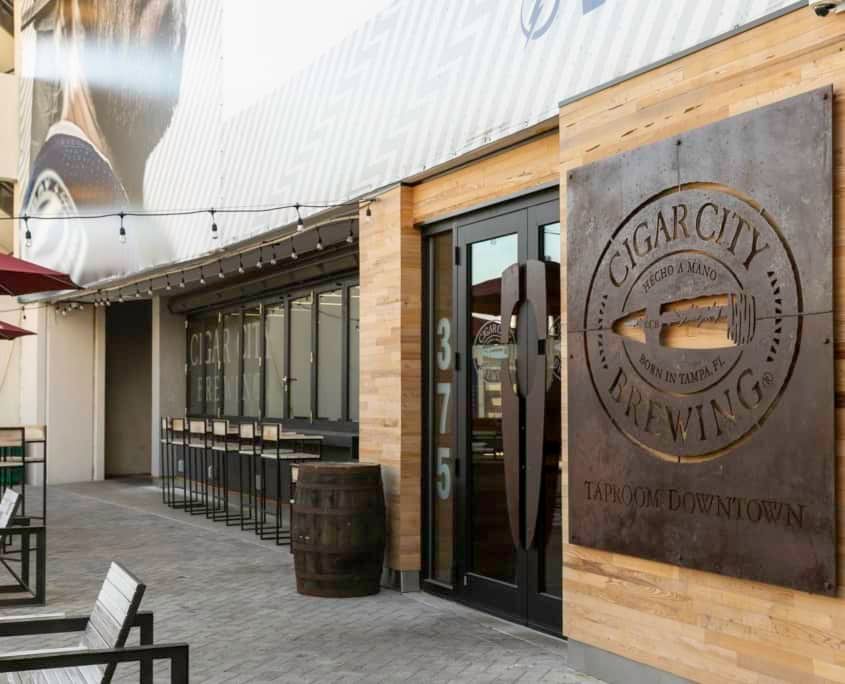 Cigar City Brewing entrance with sign, door, and barrel. Building exterior with 
