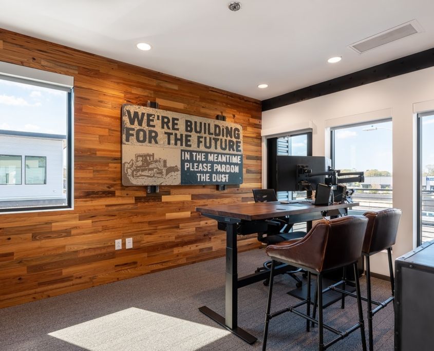 Office with wood-paneled wall, desk, and sign that says 