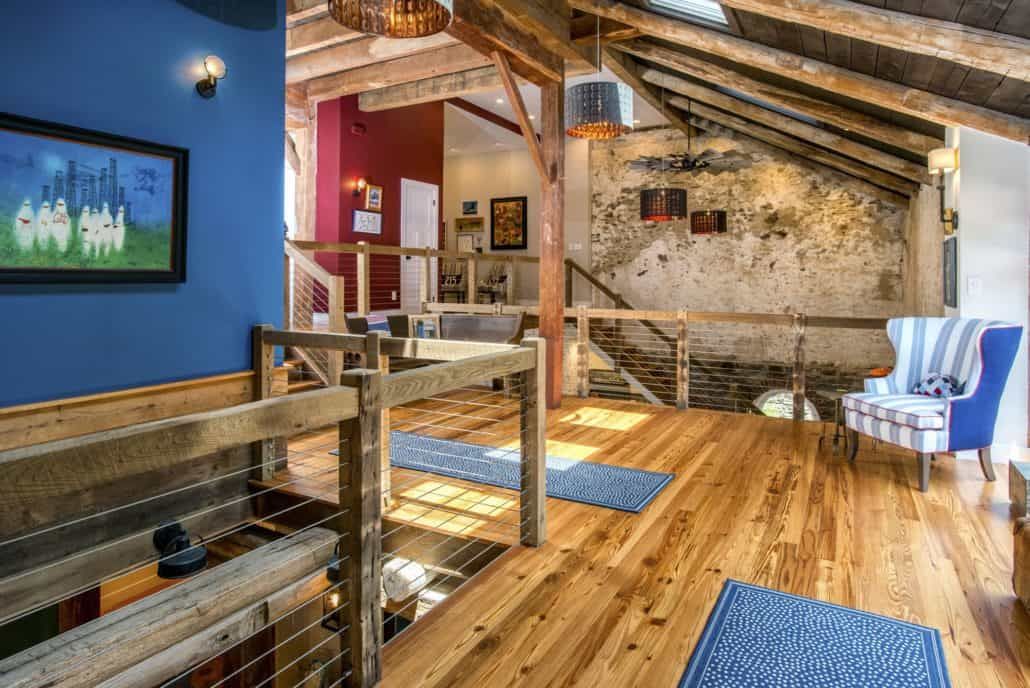 Interior view of a loft with wood floors, blue walls, and a brick wall. A blue armchair sits near a window.
