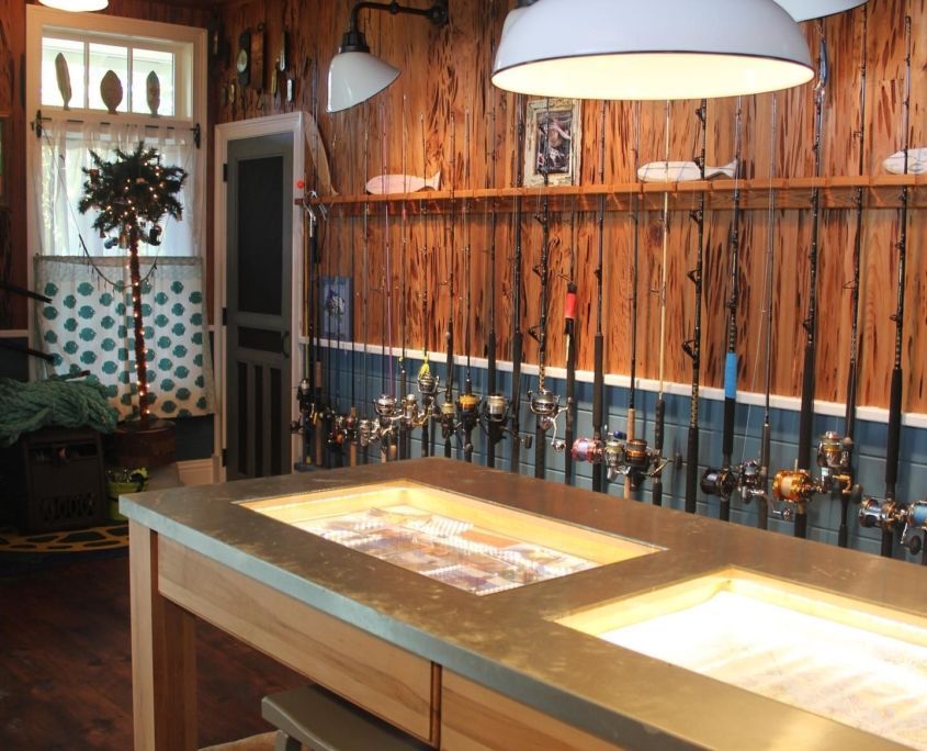 Fishing rods displayed on a wooden wall in a rustic room. Lit countertop in the foreground.