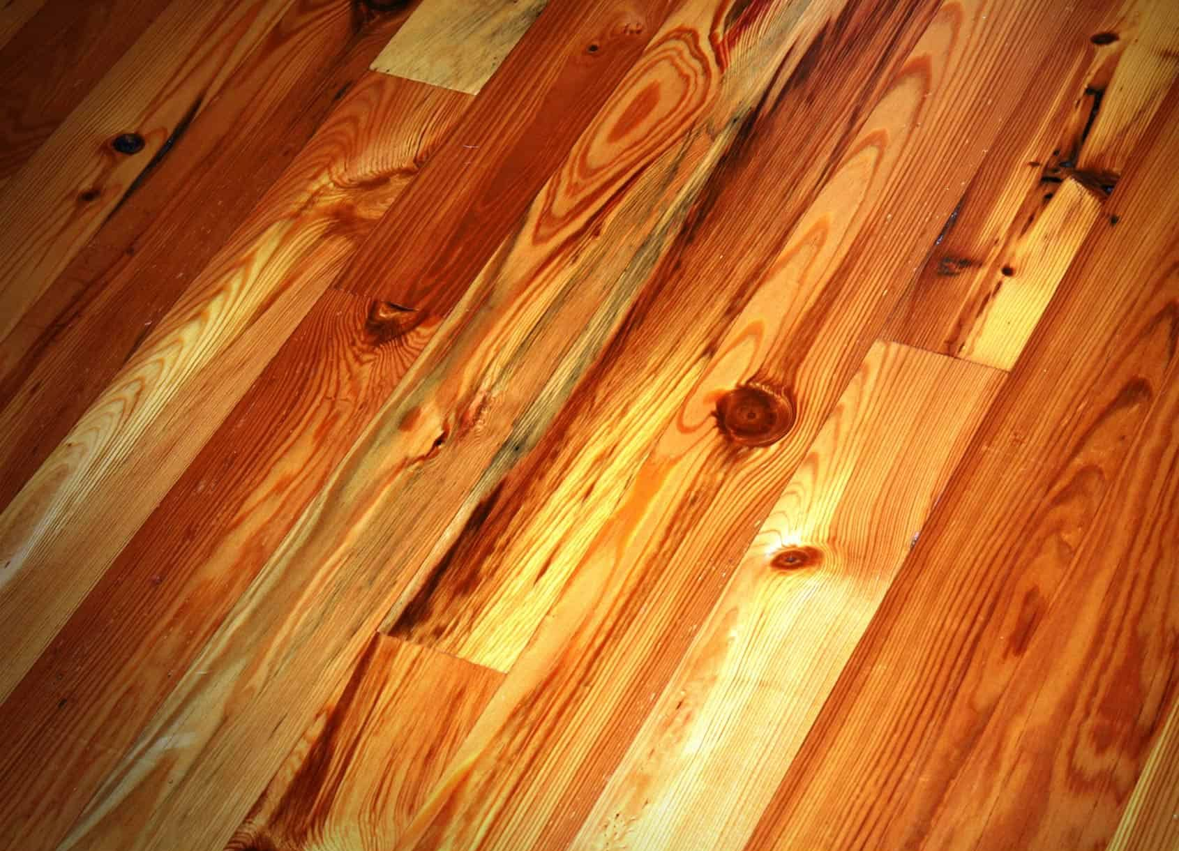 Wooden plank flooring, with knots and varying shades of golden brown and orange.