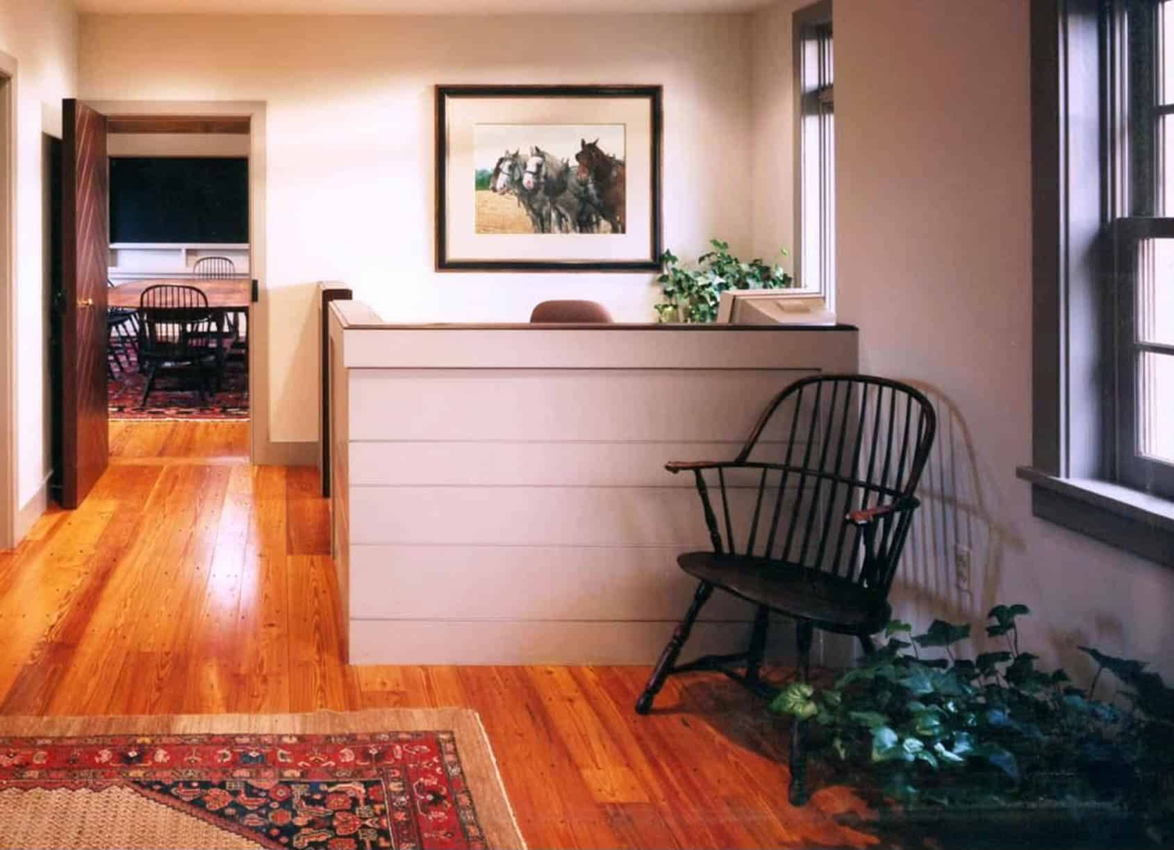 Hallway with wood floor, artwork, and black Windsor chair.