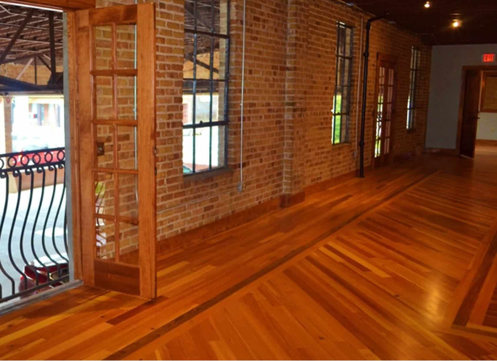 Wooden floor hallway with brick wall, glass doors, and windows.