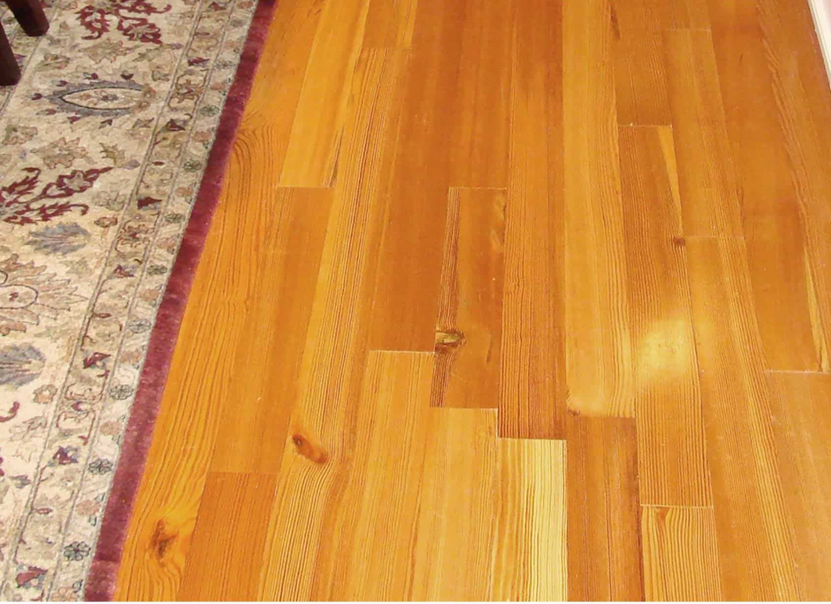 Wood floor with rug on the left side. Brown stained wood planks.
