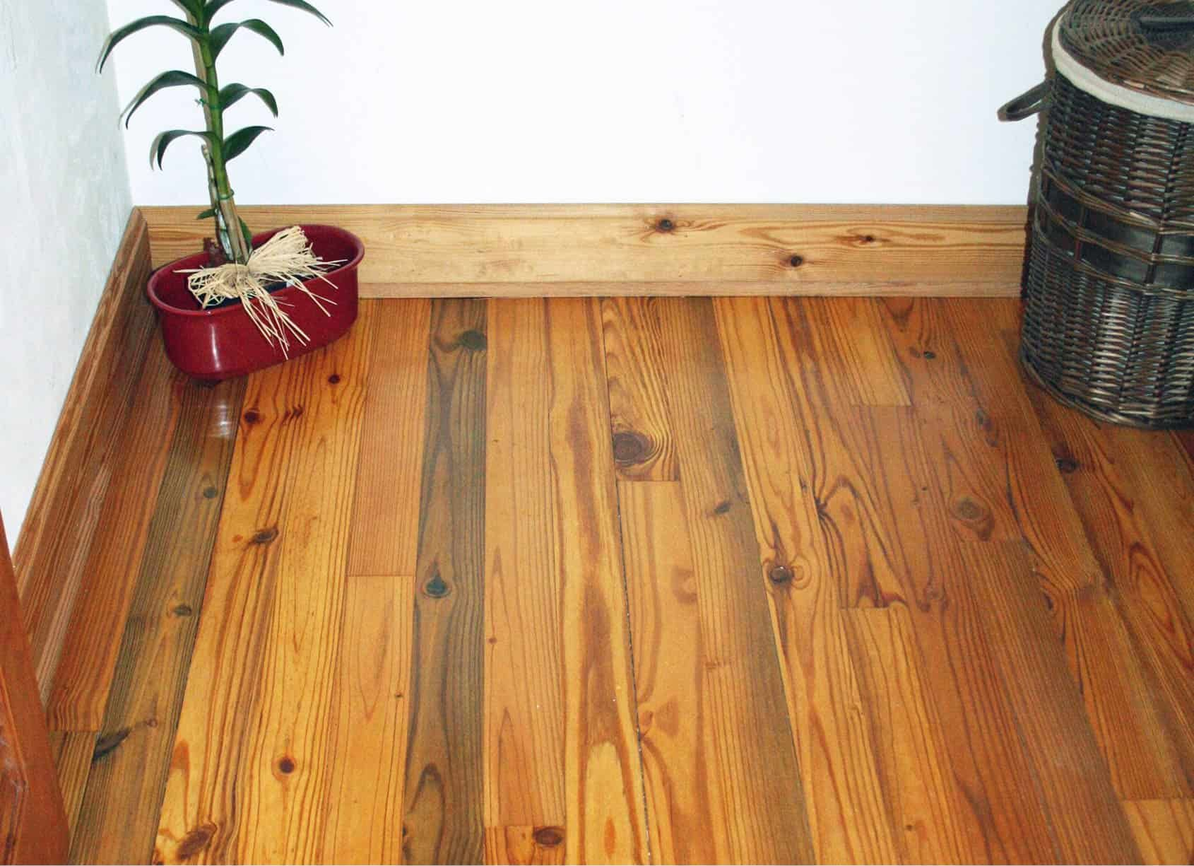 Wooden floor with a plant in a red pot and a wicker basket.