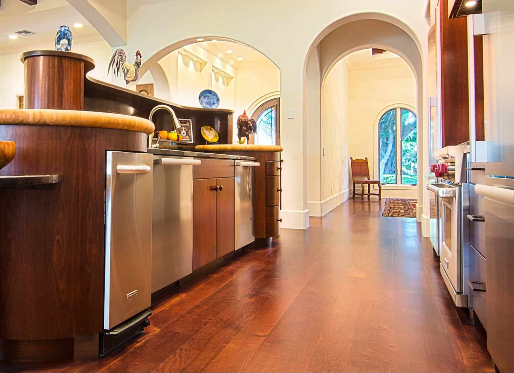 Kitchen with hardwood floors, stainless steel appliances, and arched doorways leading to another room.