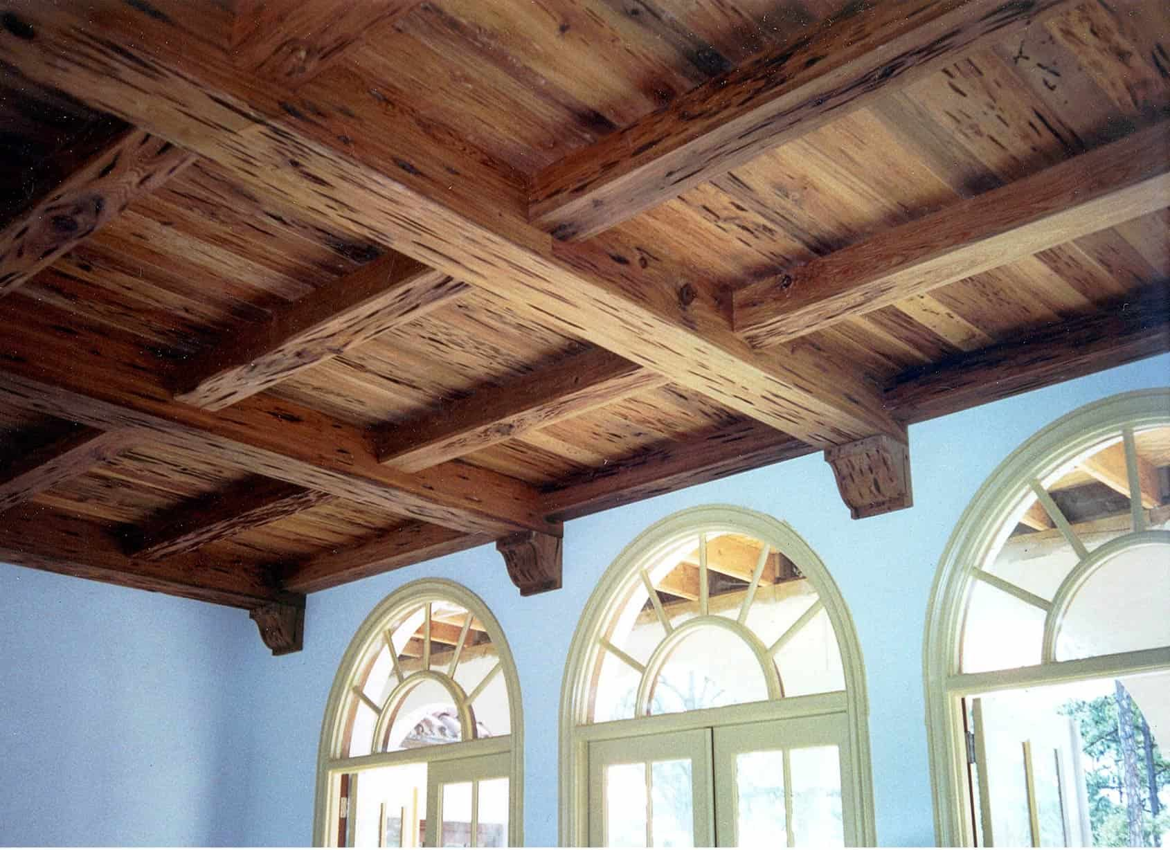 Wooden beamed ceiling with arched windows and light blue walls.