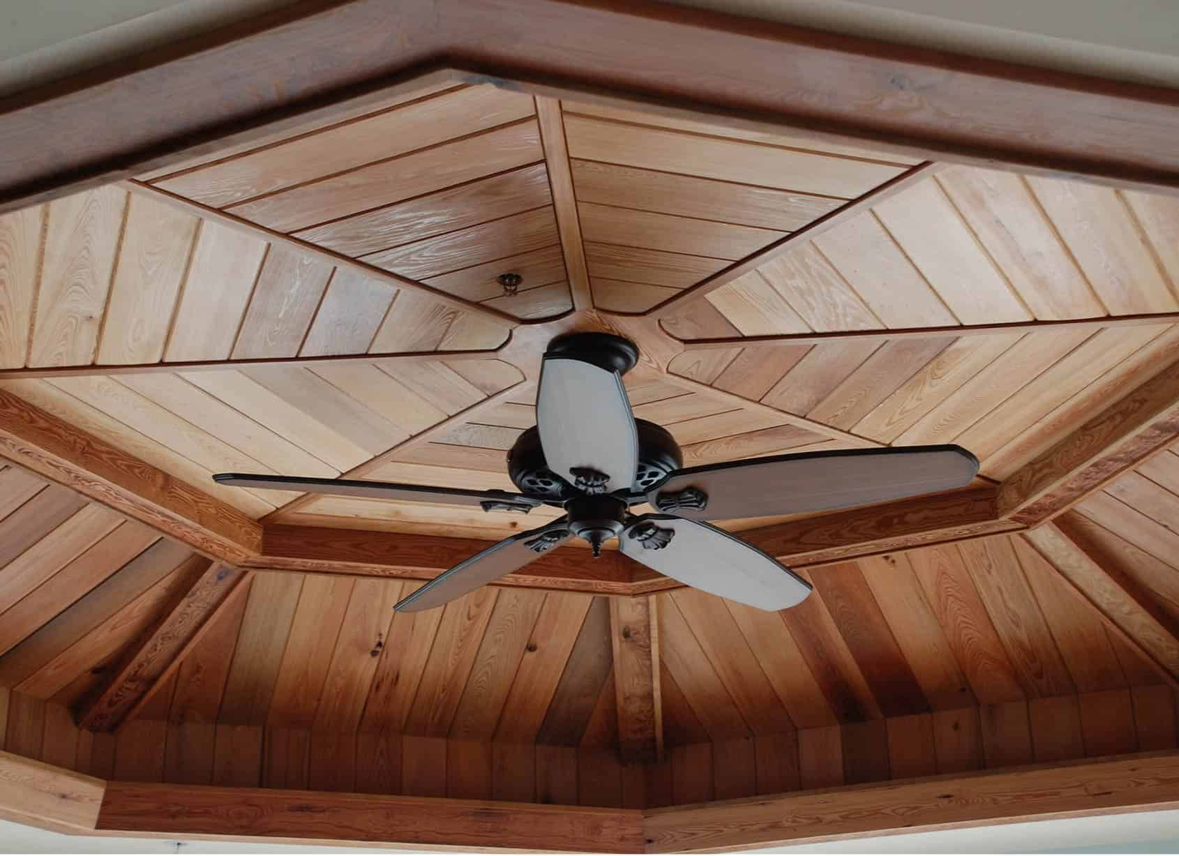 Ceiling fan with wooden blades, mounted on a wooden octagonal ceiling.