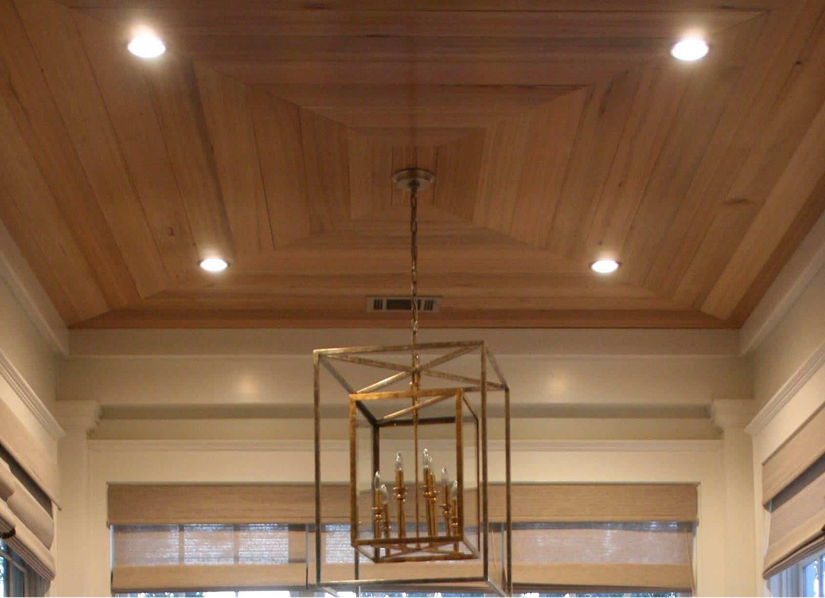 Wooden ceiling with recessed lights and a hanging gold light fixture.