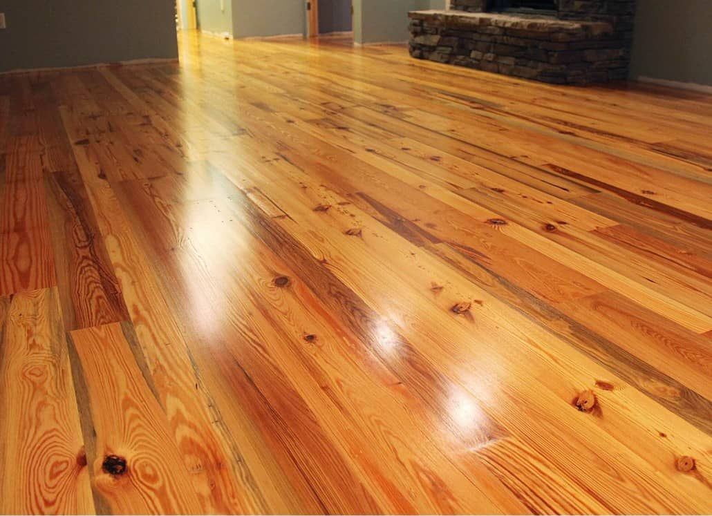 Shiny, light-colored wooden floor with knots and reflections in an interior setting.