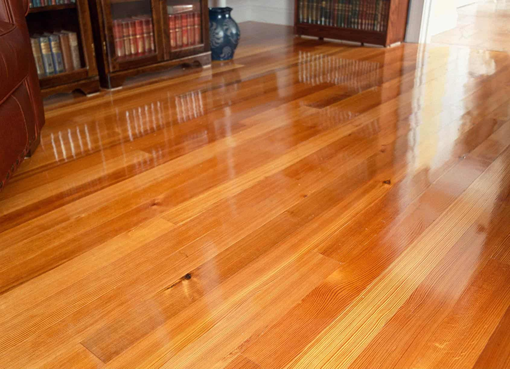 Shiny, polished hardwood floor reflecting light; a warm, natural wood tone.