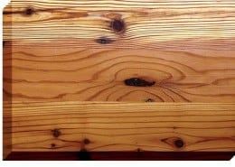 Close-up of a wooden plank with visible grain, knots, and warm brown hues.