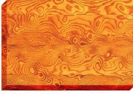 Close-up of a wood grain pattern, showcasing swirling, circular patterns in shades of orange and brown.
