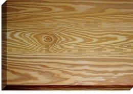 Close-up of a wooden board with prominent wood grain and a knot. Warm light brown color.