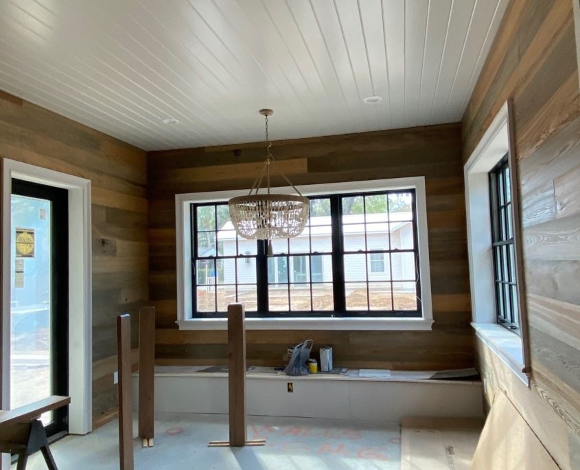 Room with wood-paneled walls and ceiling, a large window, a chandelier, and a built-in bench.