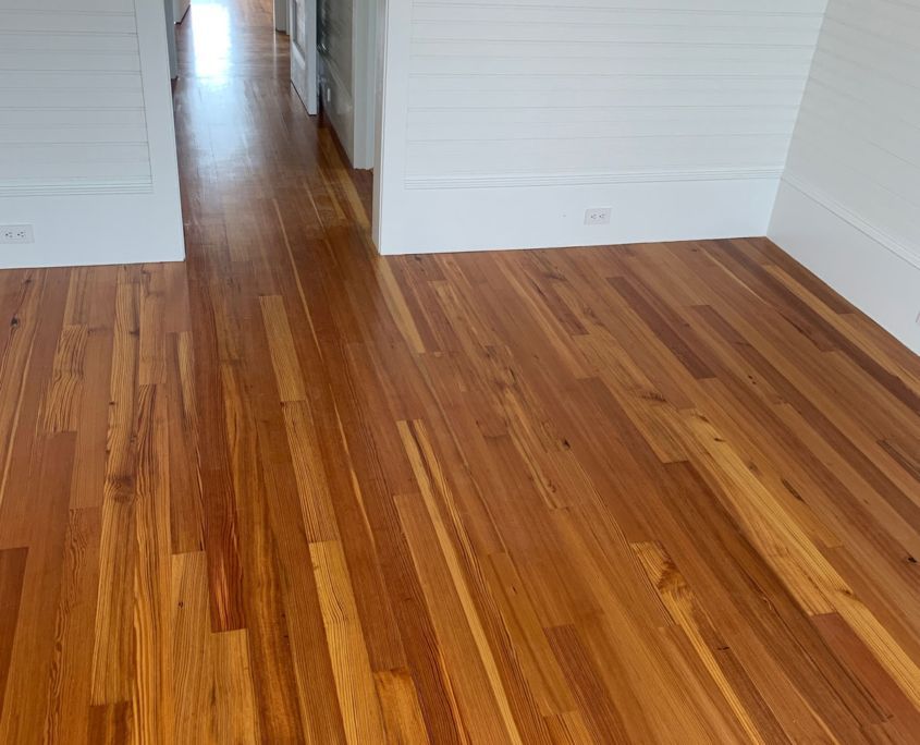 Hardwood floors in a room with white walls and trim. Light streams from a hallway in the background.
