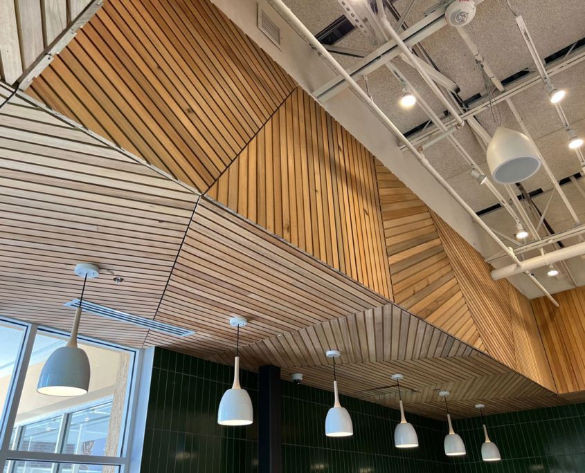 Wooden ceiling panels with hanging lights in a modern commercial space.