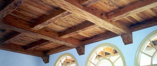 Wooden ceiling with exposed beams and arched windows below.
