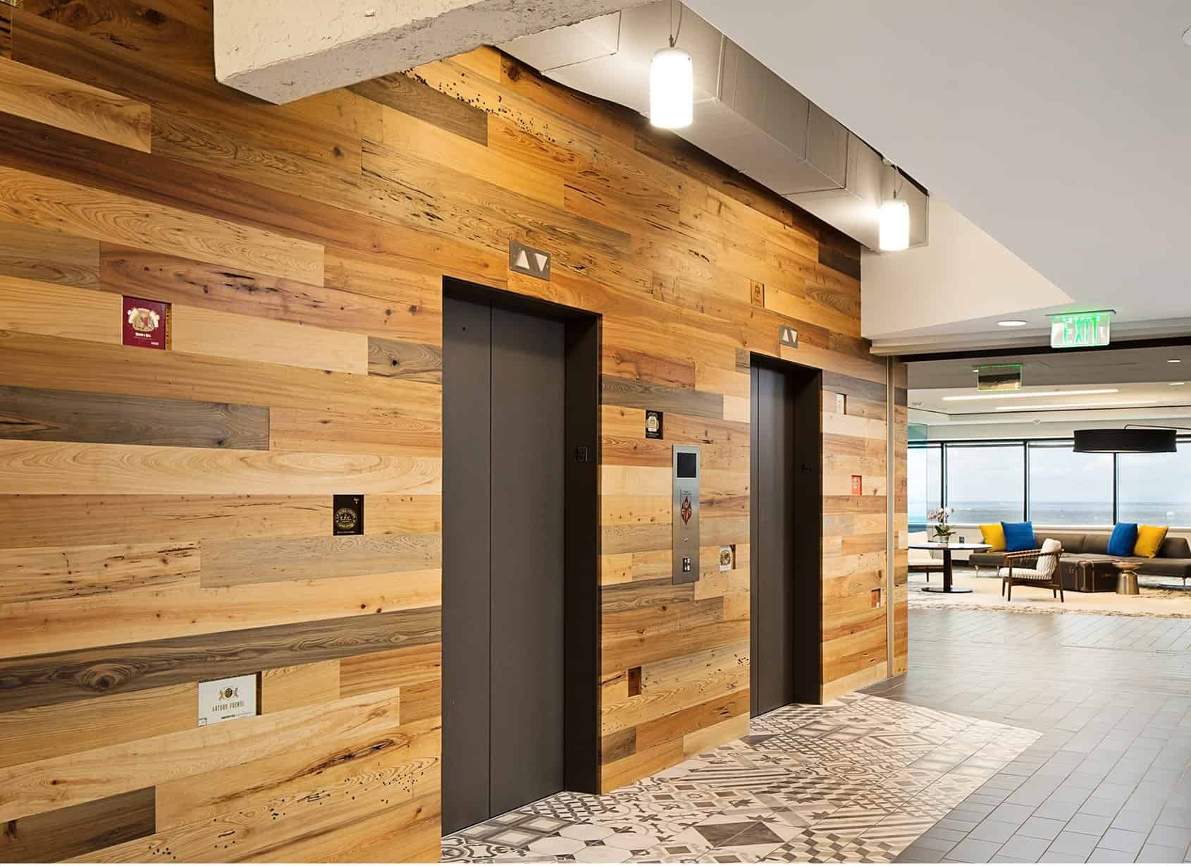 Elevator lobby with wood-paneled walls, two gray elevator doors, and patterned floor tiles.