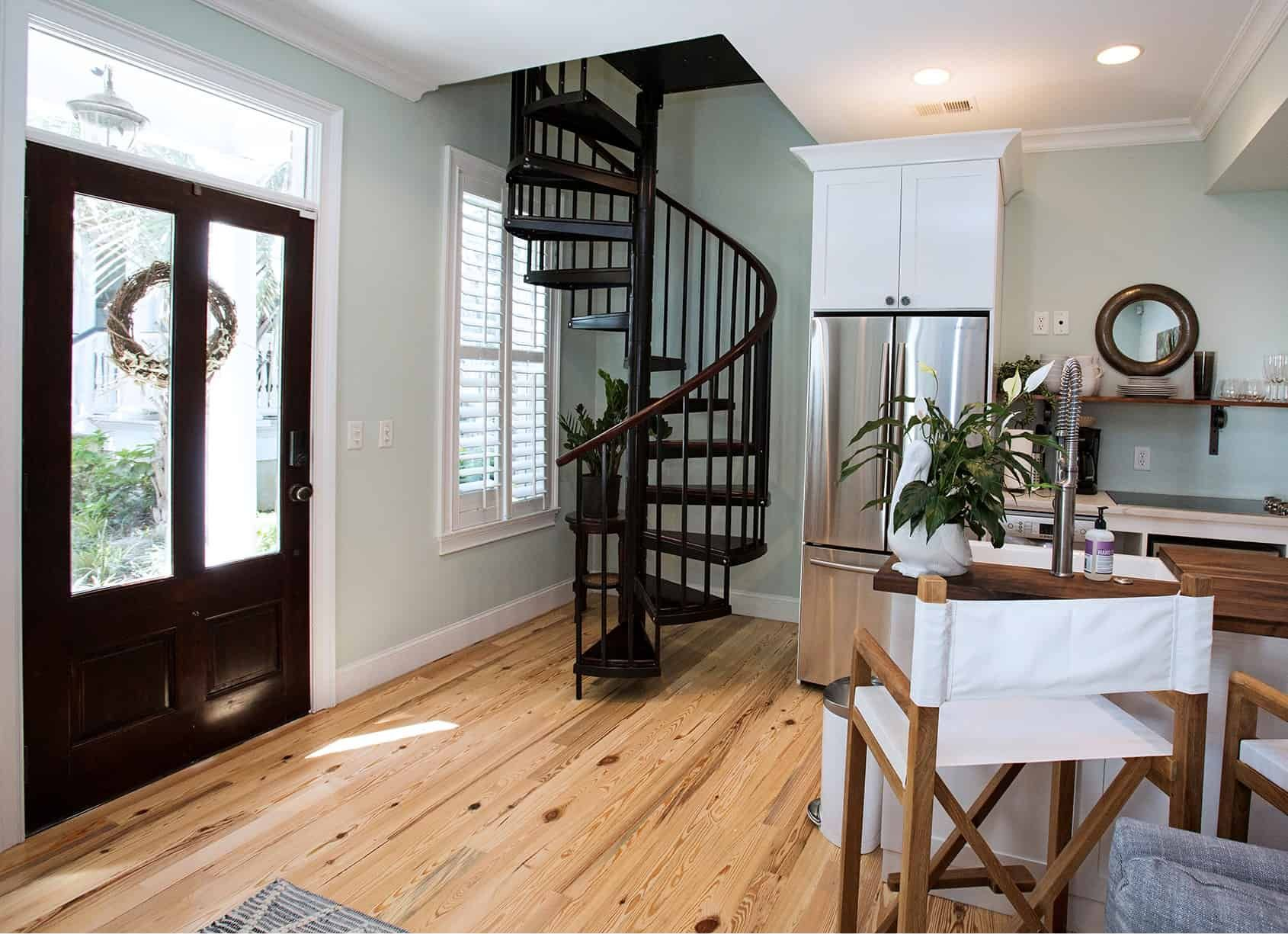 Wooden-floored interior with spiral staircase, dark door, and small kitchen area.