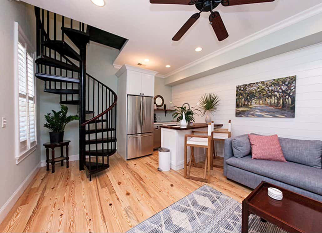 Cozy living space with spiral staircase, kitchen, sofa, and wooden floors.