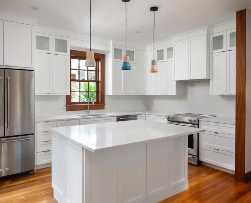 Bright white kitchen with a center island and wood flooring. Stainless steel appliances.