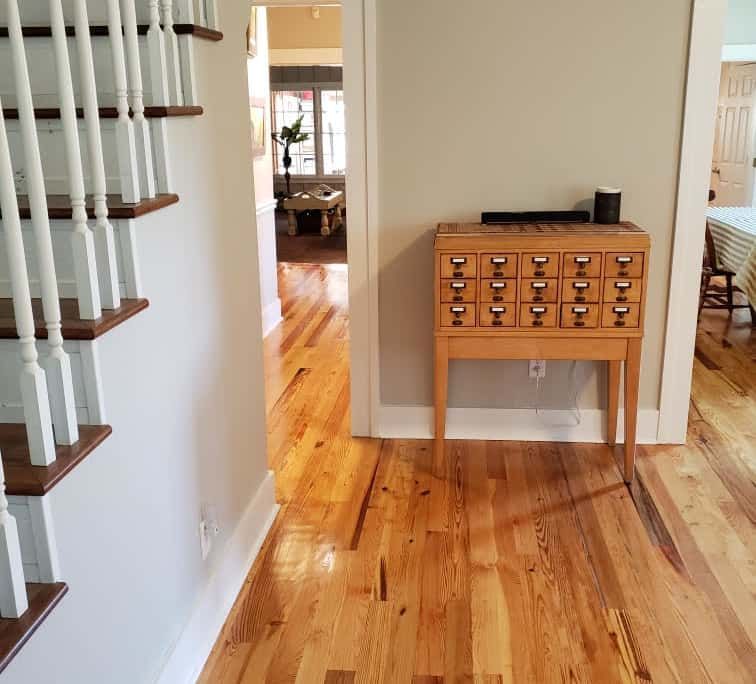 Wooden staircase and hallway with wood floors, small cabinet with drawers against wall.
