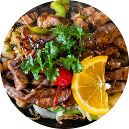 Grilled beef and vegetables topped with parsley, a red chili, and an orange slice on a dark plate
