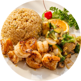 Plate of shrimp, grilled chicken, brown rice, and sautéed vegetables with lemon and herbs