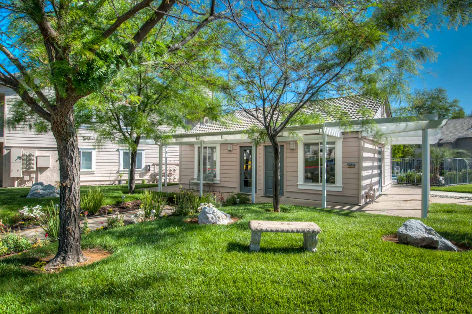 Another view of the office at Shasta Creek Apartments including a stone bench and garden
