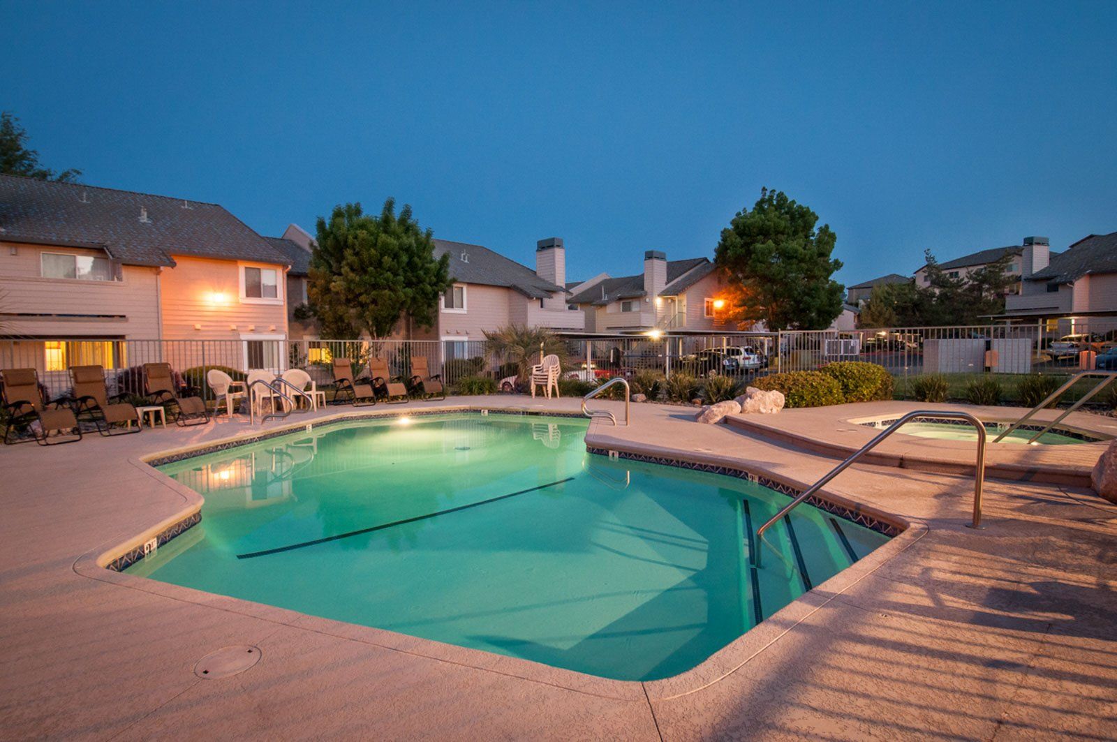 A view of the pool, hot tub, and exterior of the building at night