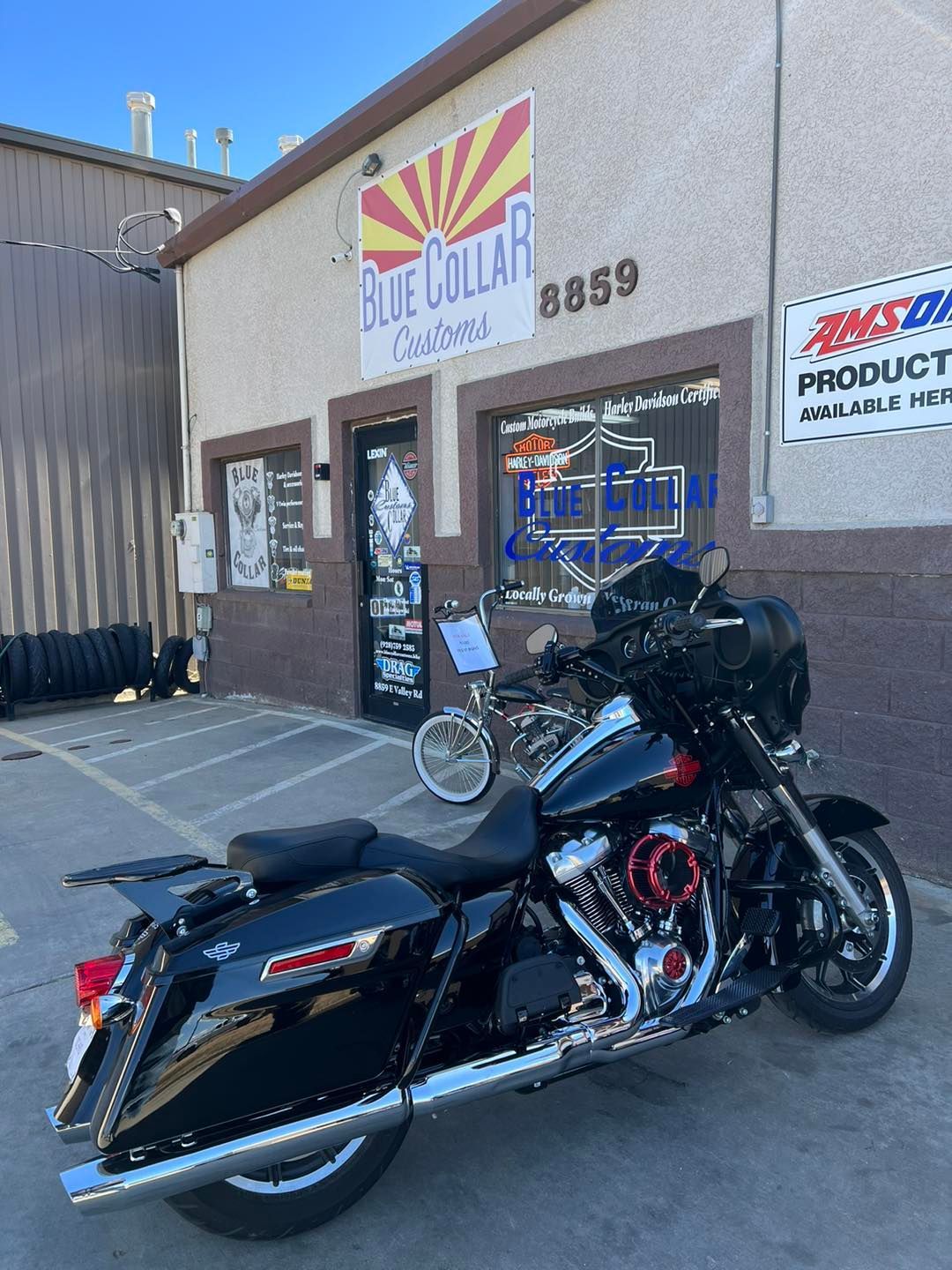 A black touring motorcycle parked in front of a shop named Blue Collar Customs with an Arizona-themed logo.