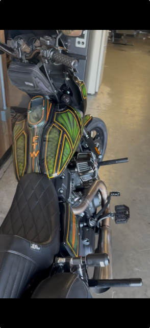 A high-angle view of a custom Harley-Davidson motorcycle with green and black patterned tank graphics and a black seat.