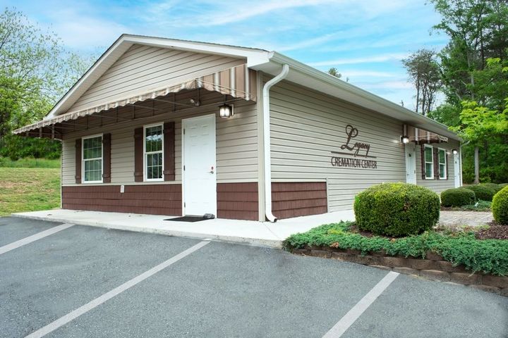 Small beige office building with a white door, brown trim, and parking lot in front