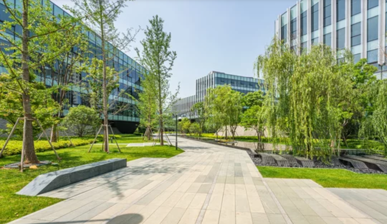 A large building with a lot of windows is surrounded by trees and grass.