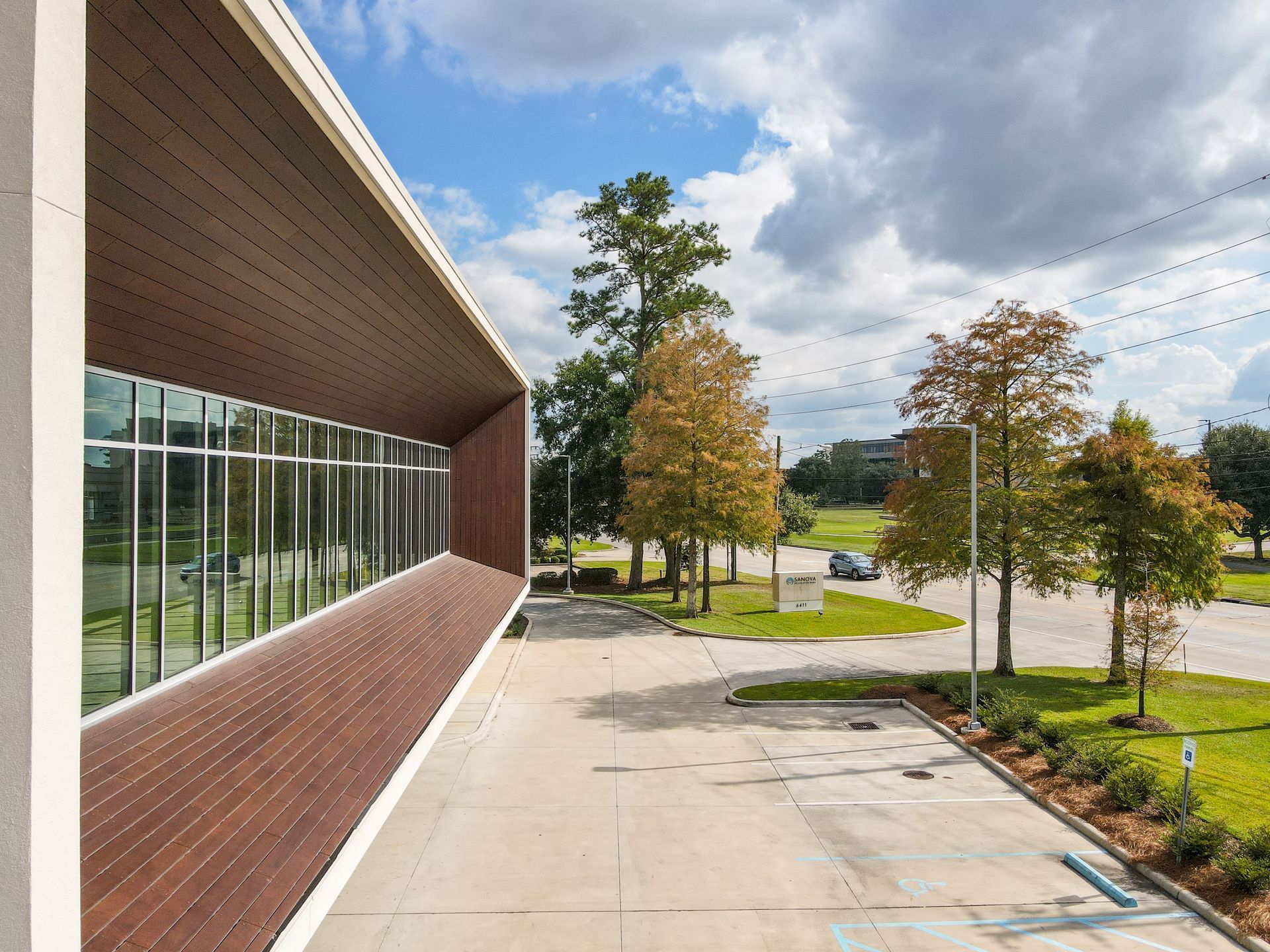 A large building with a lot of windows is surrounded by trees and a parking lot.