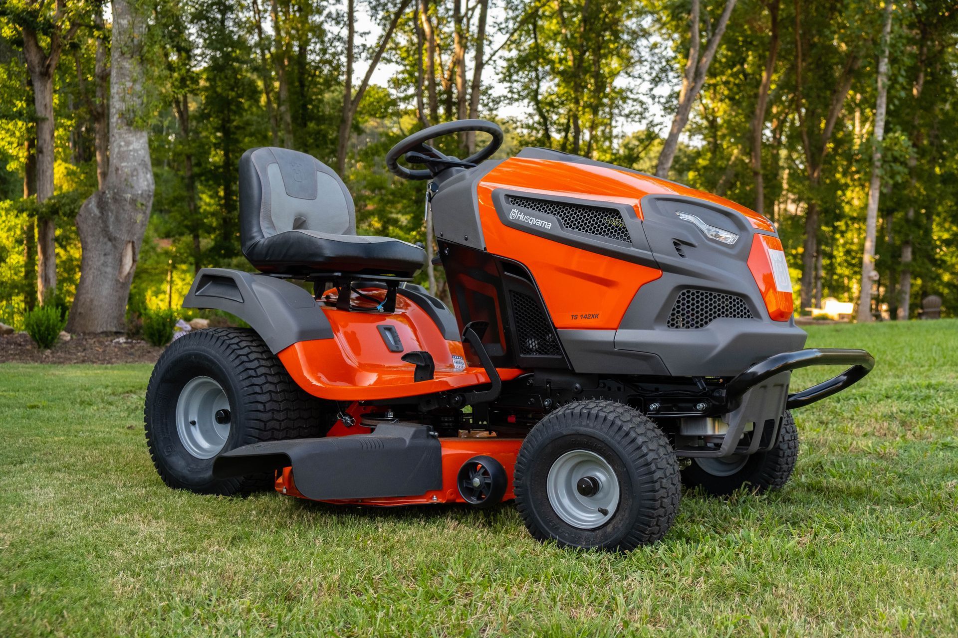 An orange and black lawn mower is parked on a lush green lawn.