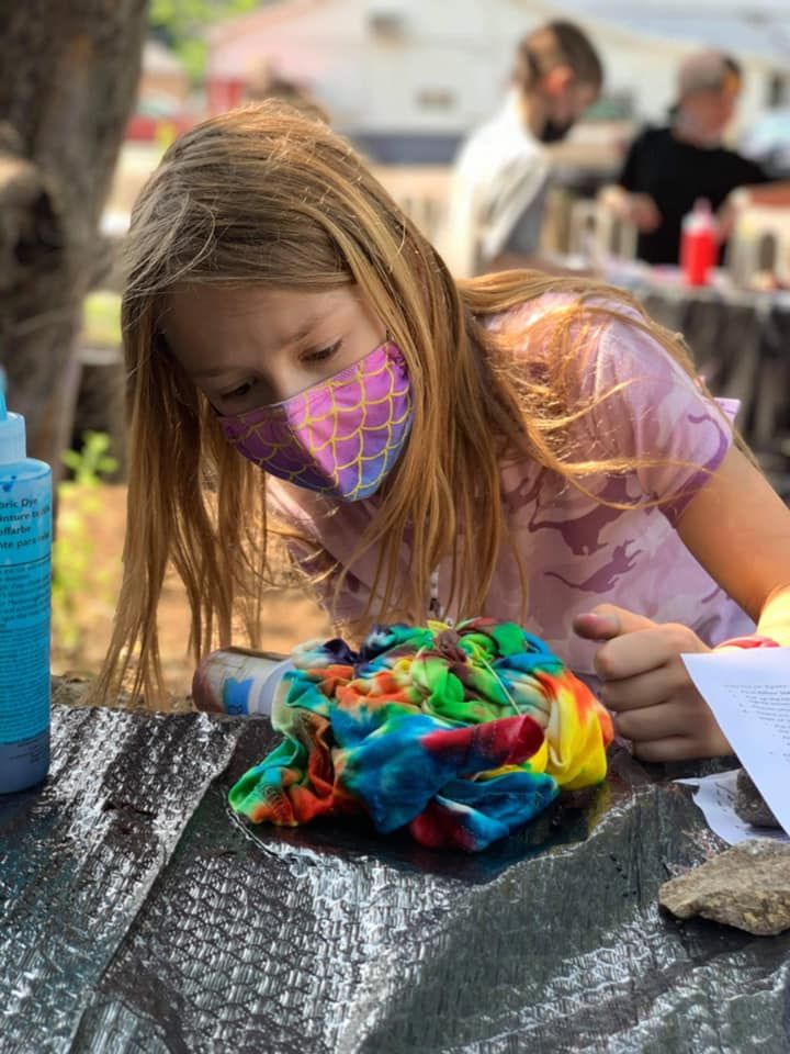 A young girl wearing a mask is sitting at a table