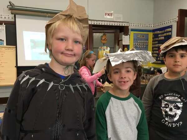 A group of young boys are posing for a picture in a classroom with an exit sign in the background