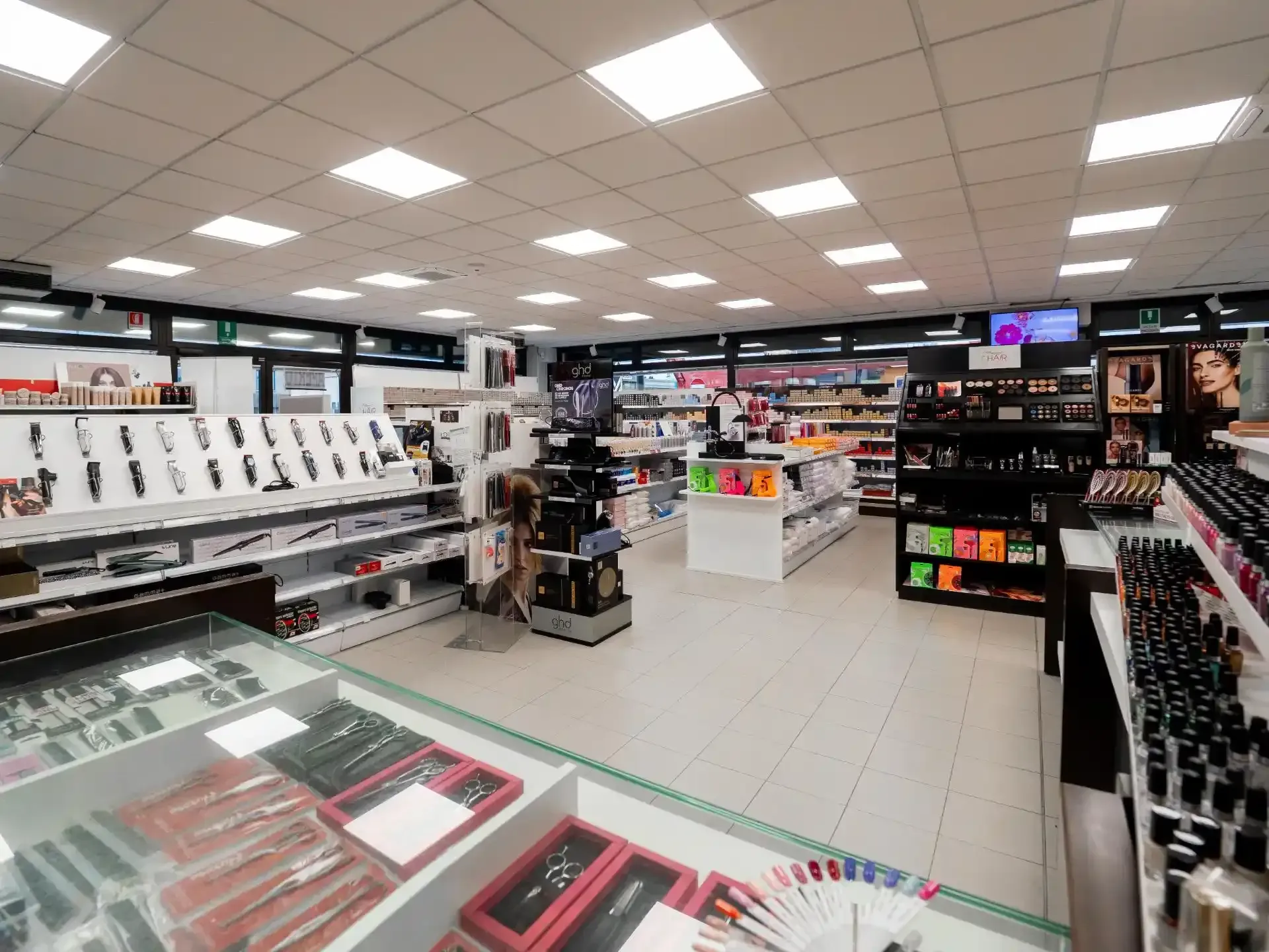 Interno di un negozio di prodotti di bellezza con file di prodotti esposti sotto una luce intensa.