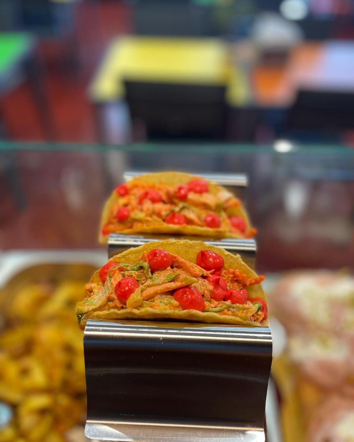 Una fila di tacos appoggiata sopra un vassoio di metallo.