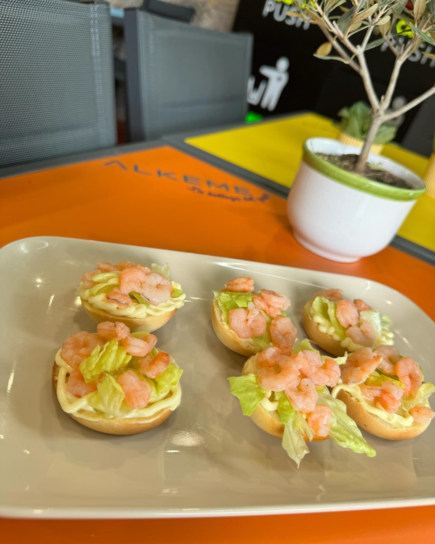 Un piatto di cibo con gamberetti e lattuga su un tavolo.
