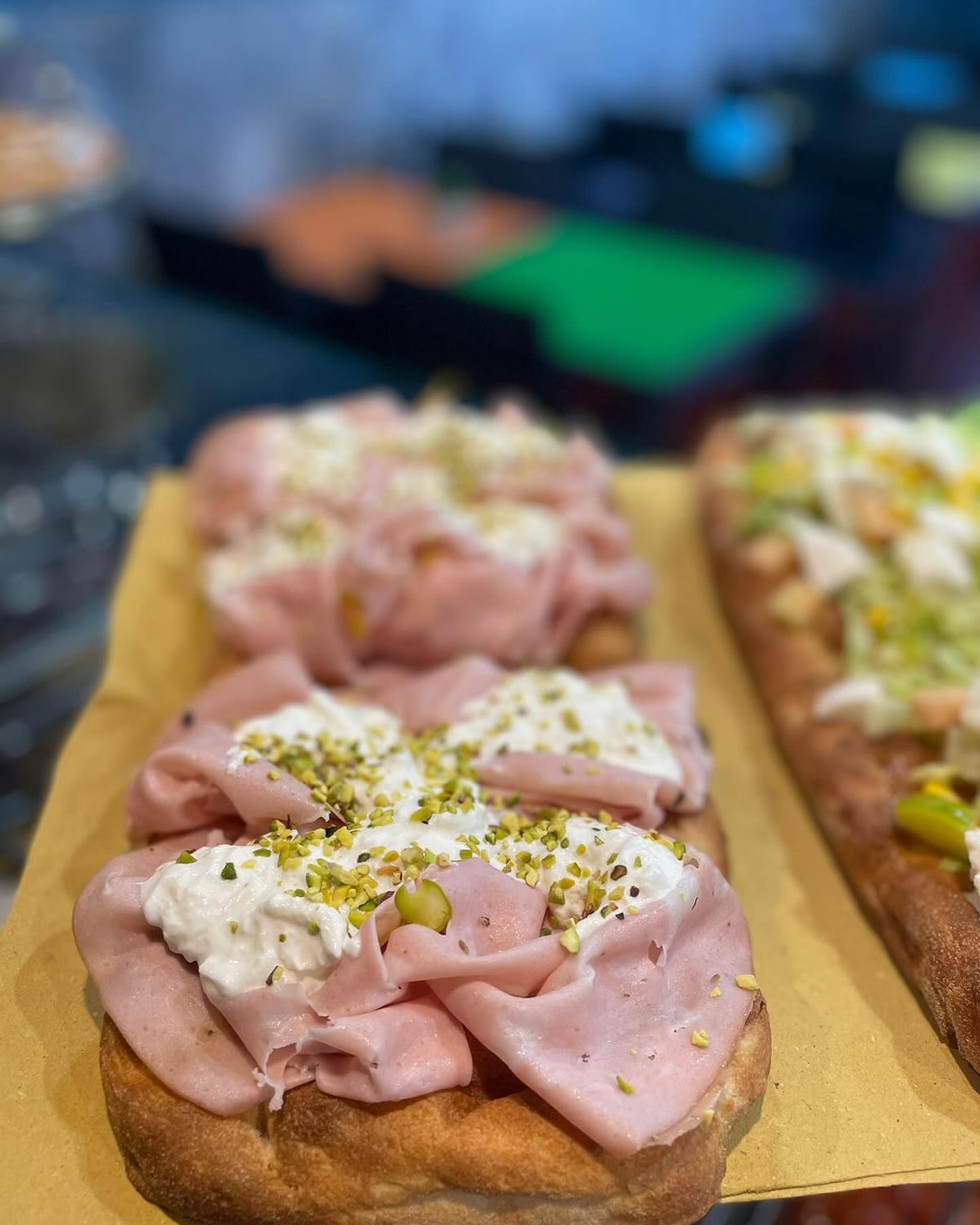 Un primo piano di una pizza con prosciutto e formaggio su un tavolo.