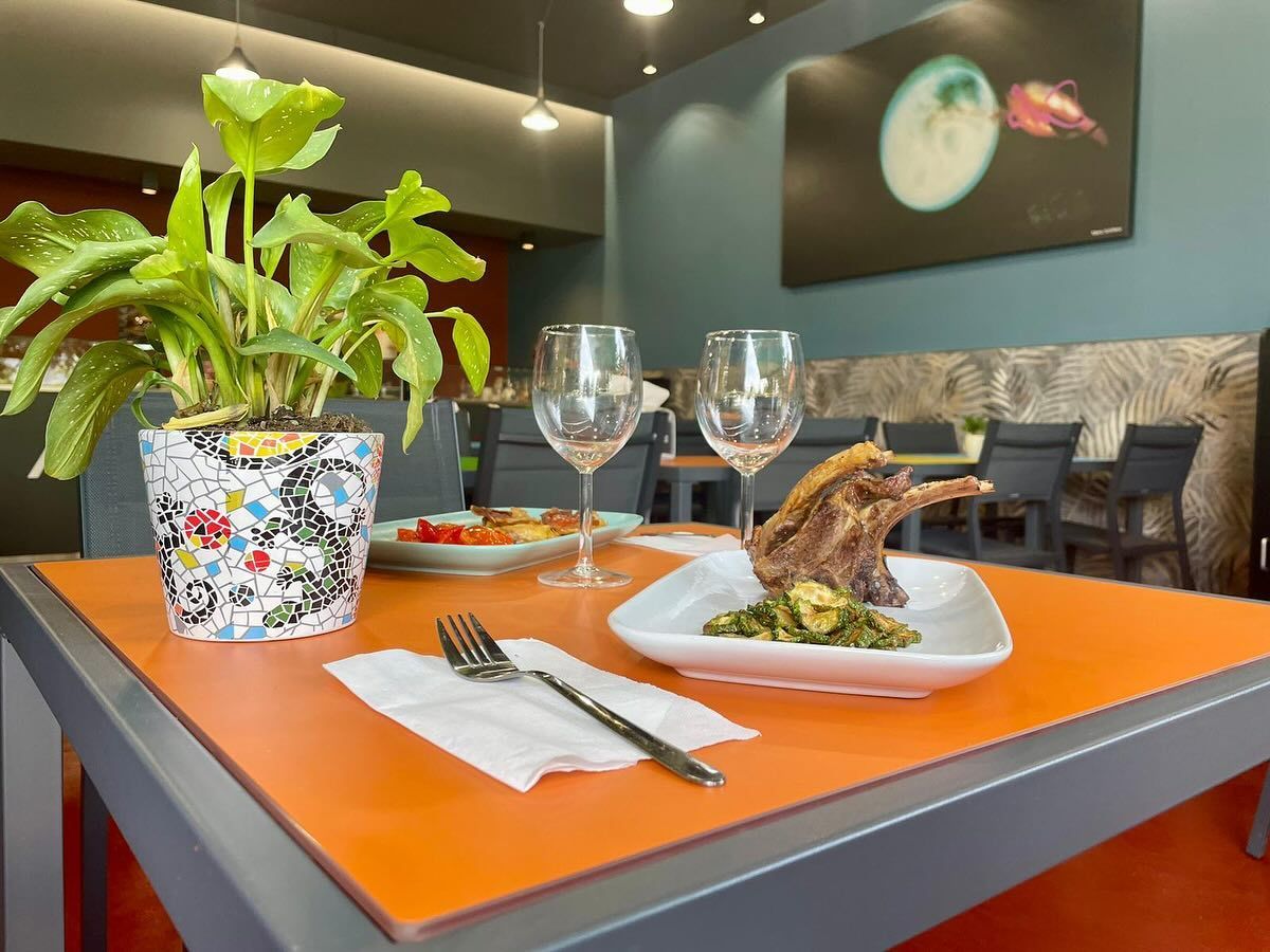 Un tavolo con sopra un piatto di cibo e bicchieri di vino nel ristorante Alkeme