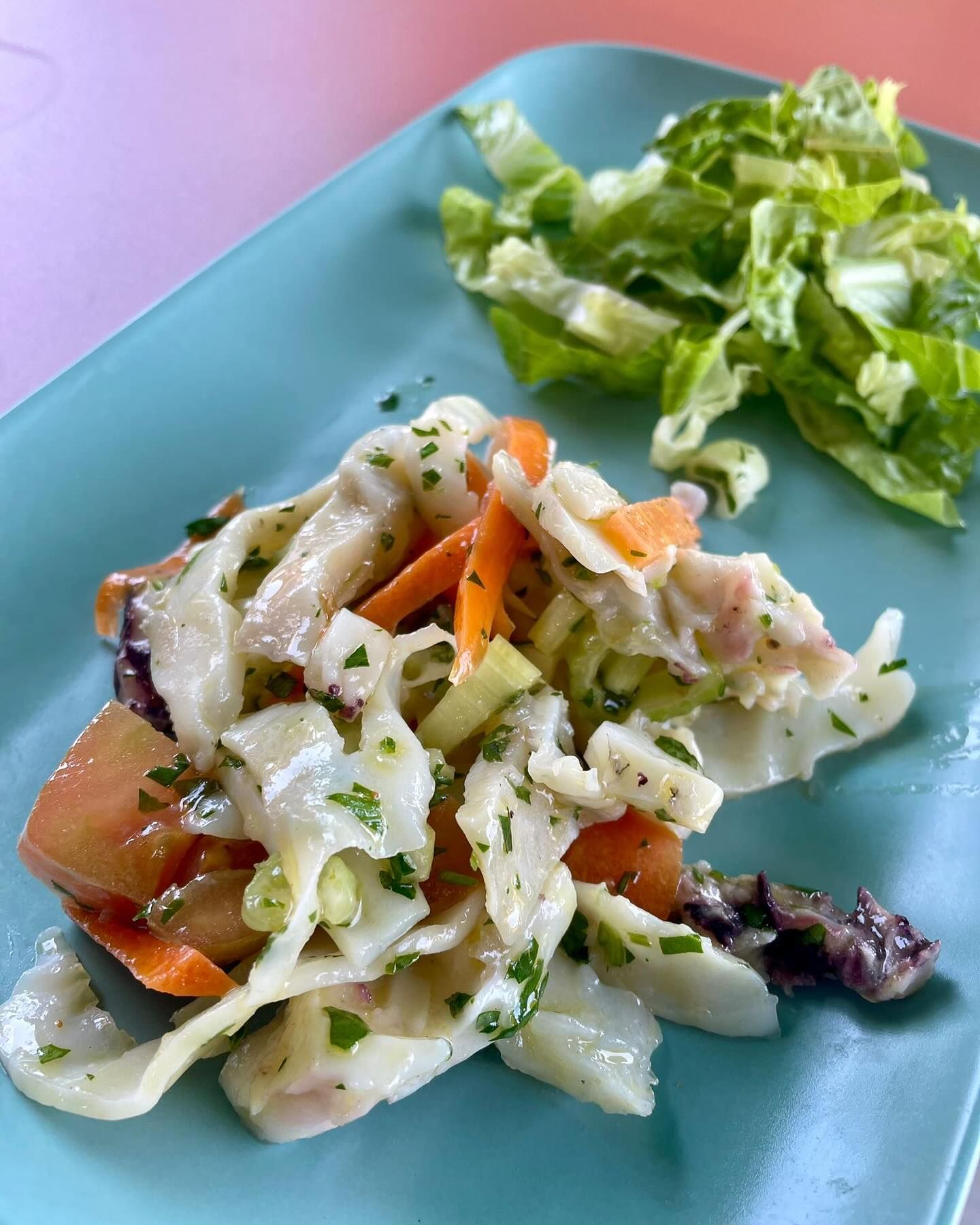 Un piatto di cibo con un'insalata a parte su un tavolo.