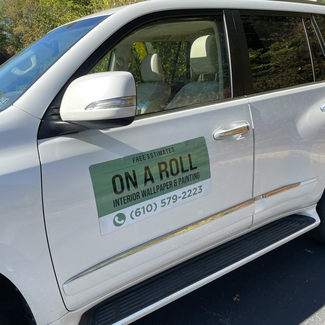 A white suv with a sign on the door that says on a roll